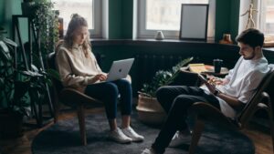 Two people sitting in a well-decorated living room working on laptops