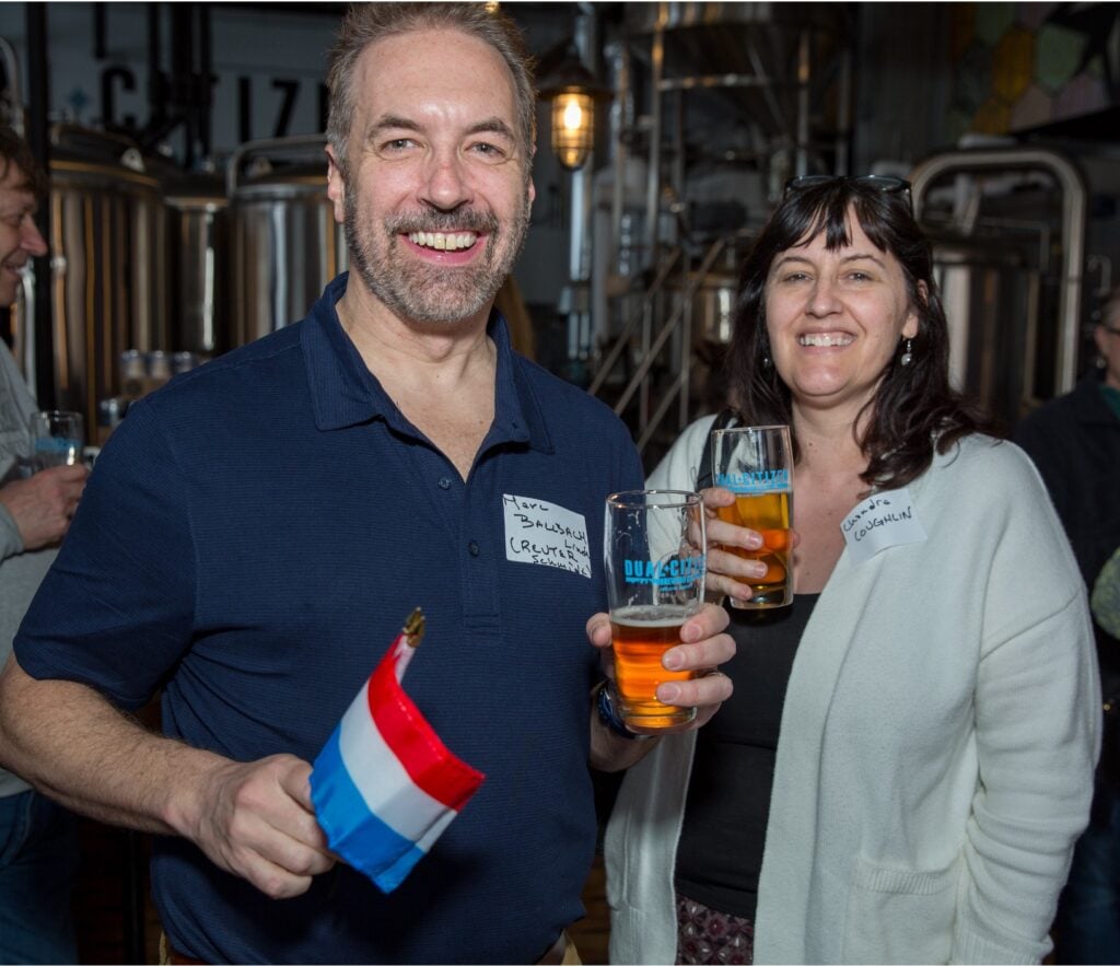 Two people holding drinks and Luxembourg flags