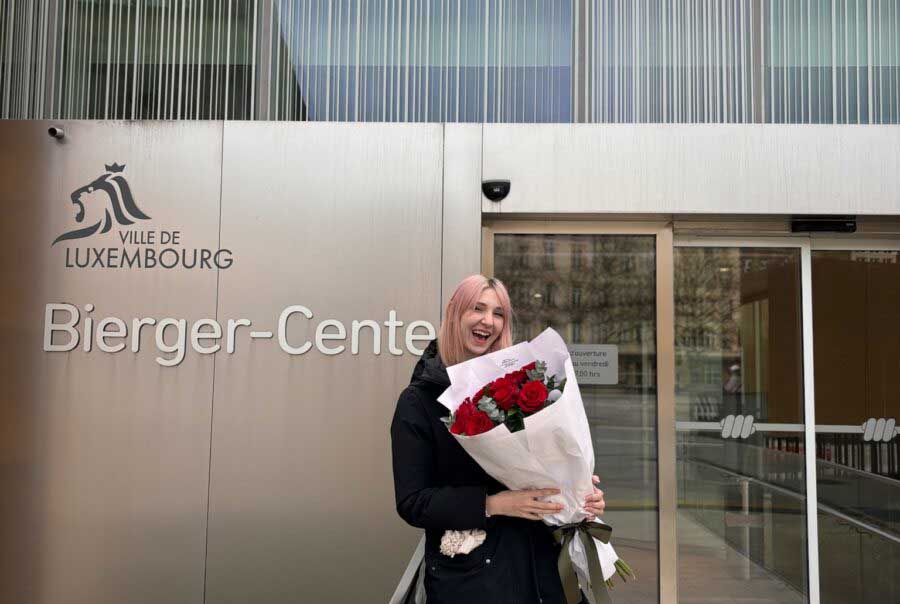 Person holding flowers in front of Luxembourg citizenship center