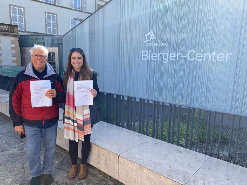 Two LuxCitizenship clients holding their Luxembourg citizenship declarations outside the Bierger-Center in Luxembourg City