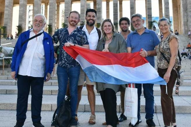 Argentine-Luxembourgers holding a Luxembourg flag on the steps of a monument