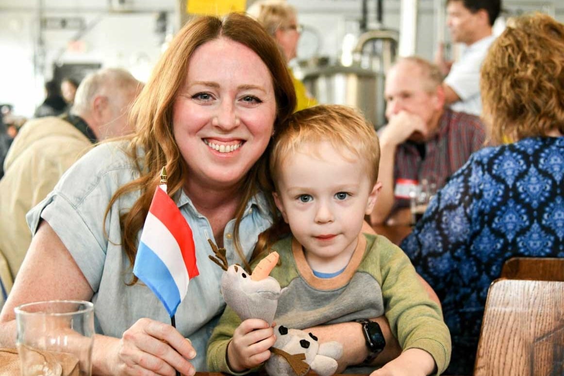 An American-Luxembourger and her young son holding a Luxembourg flag at a LuxCitizenship event